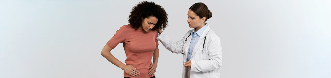 Medica consolando paciente com mao no quadril indicando dor