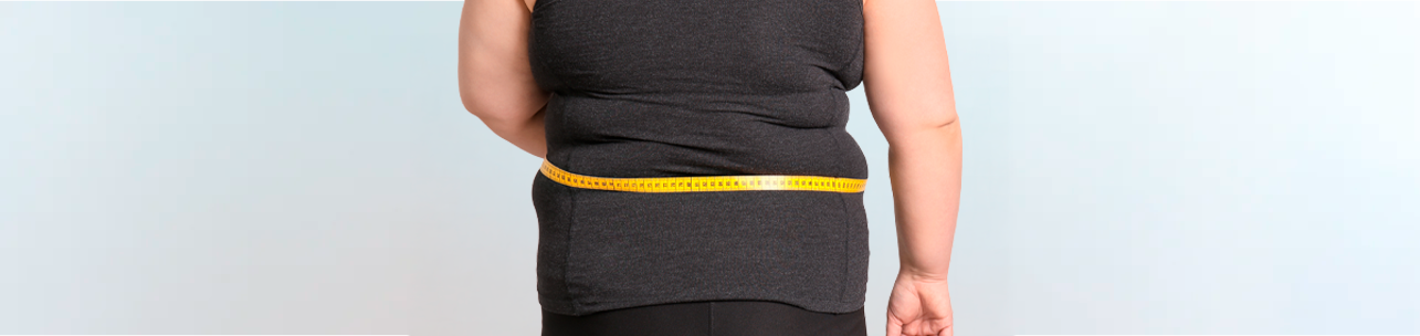 Uma pessoa de costas, vestindo uma regata escura, com uma fita métrica amarela ao redor da cintura